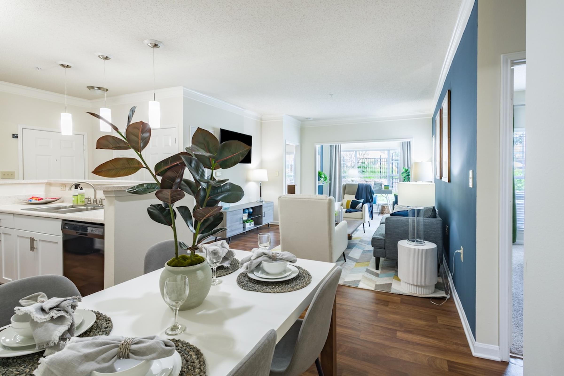 a dining room and living room area with a white table and chairs and a blue accent wall