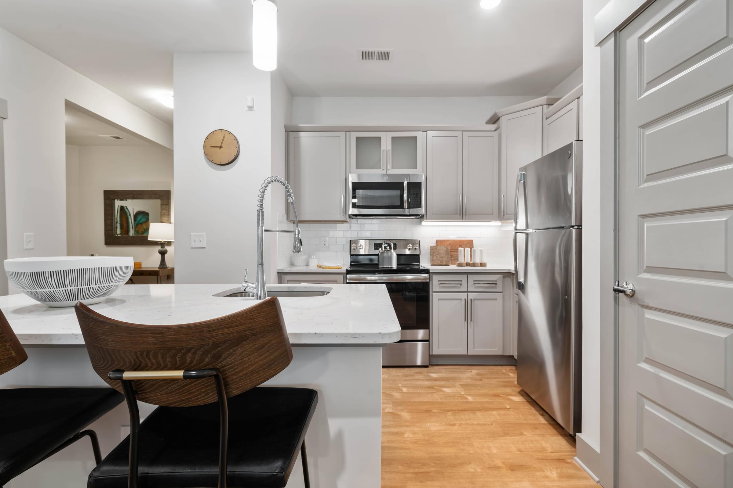A modern kitchen with a wooden chair and a white countertop.