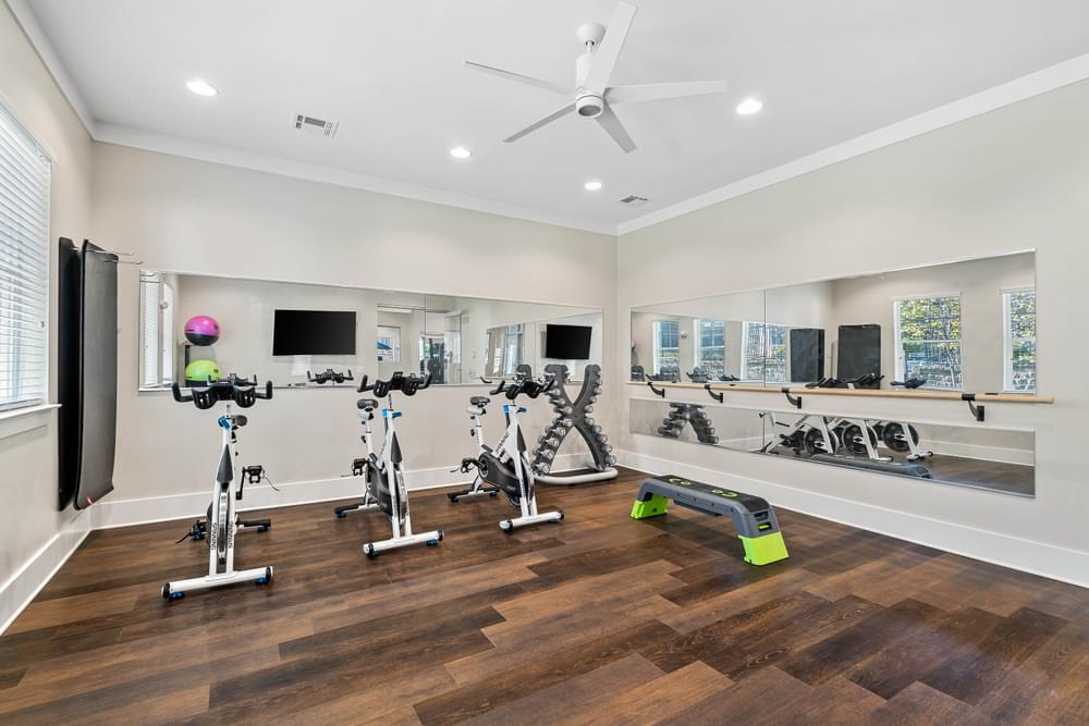 an apartment  gym with treadmills and weights and a ceiling fan