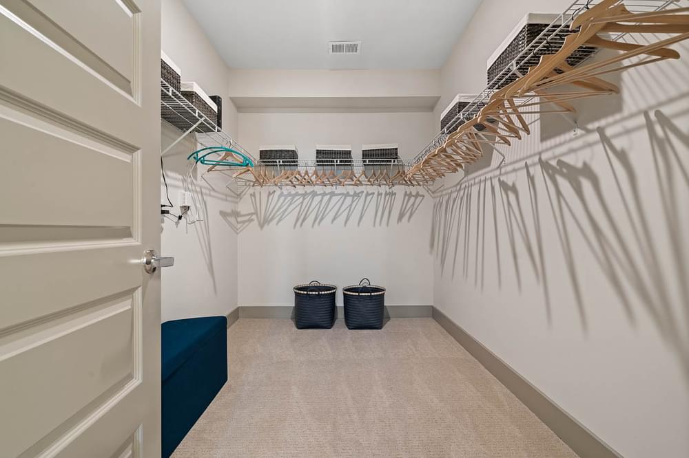 a large walk in closet with baskets and a rack of clothes