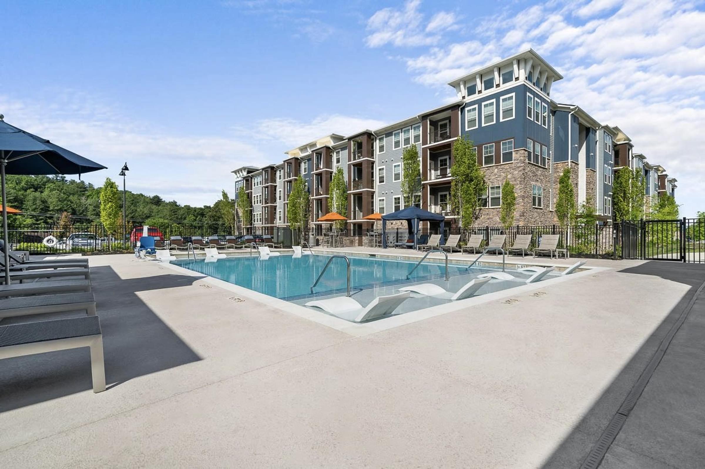 A large swimming pool in front of a multi-story apartment building.