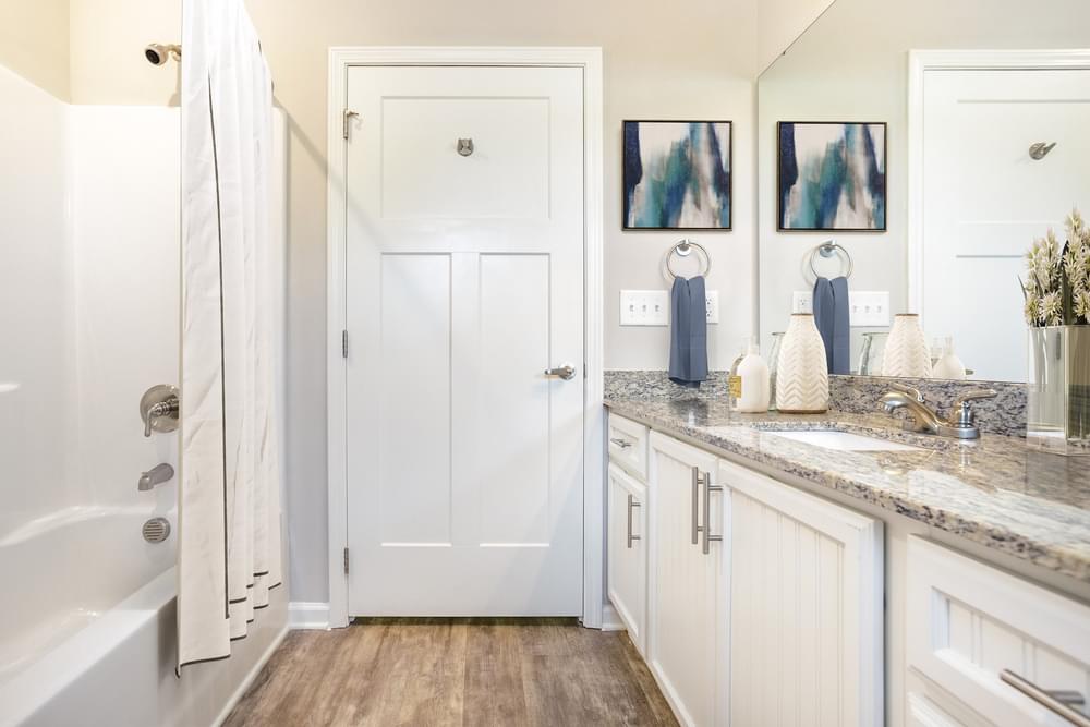 a bathroom with white cabinets and a shower and a sink