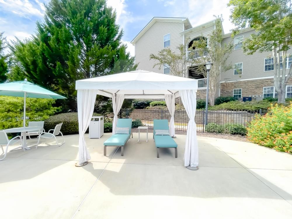 a white gazebo with chairs and umbrellas on a patio
