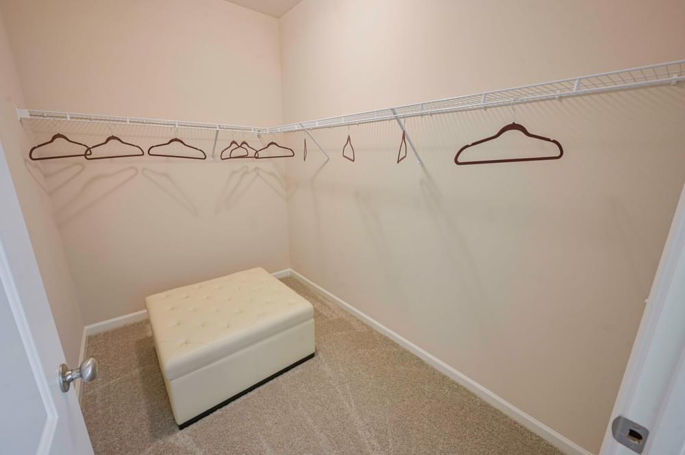 a closet with a white bench and clothes hangers on the wall