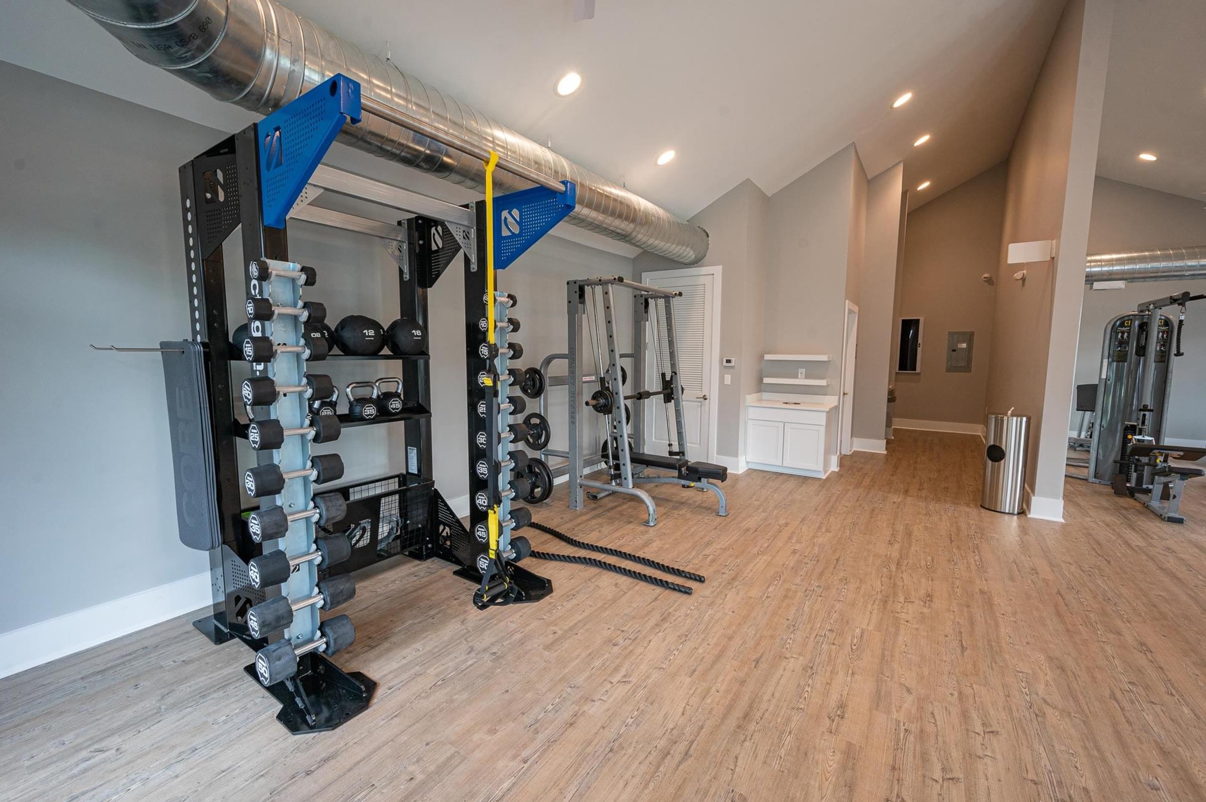 a home gym with weights and equipment on a wooden floor