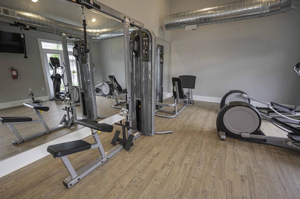 a gym with weights and cardio equipment in a room with wood floors