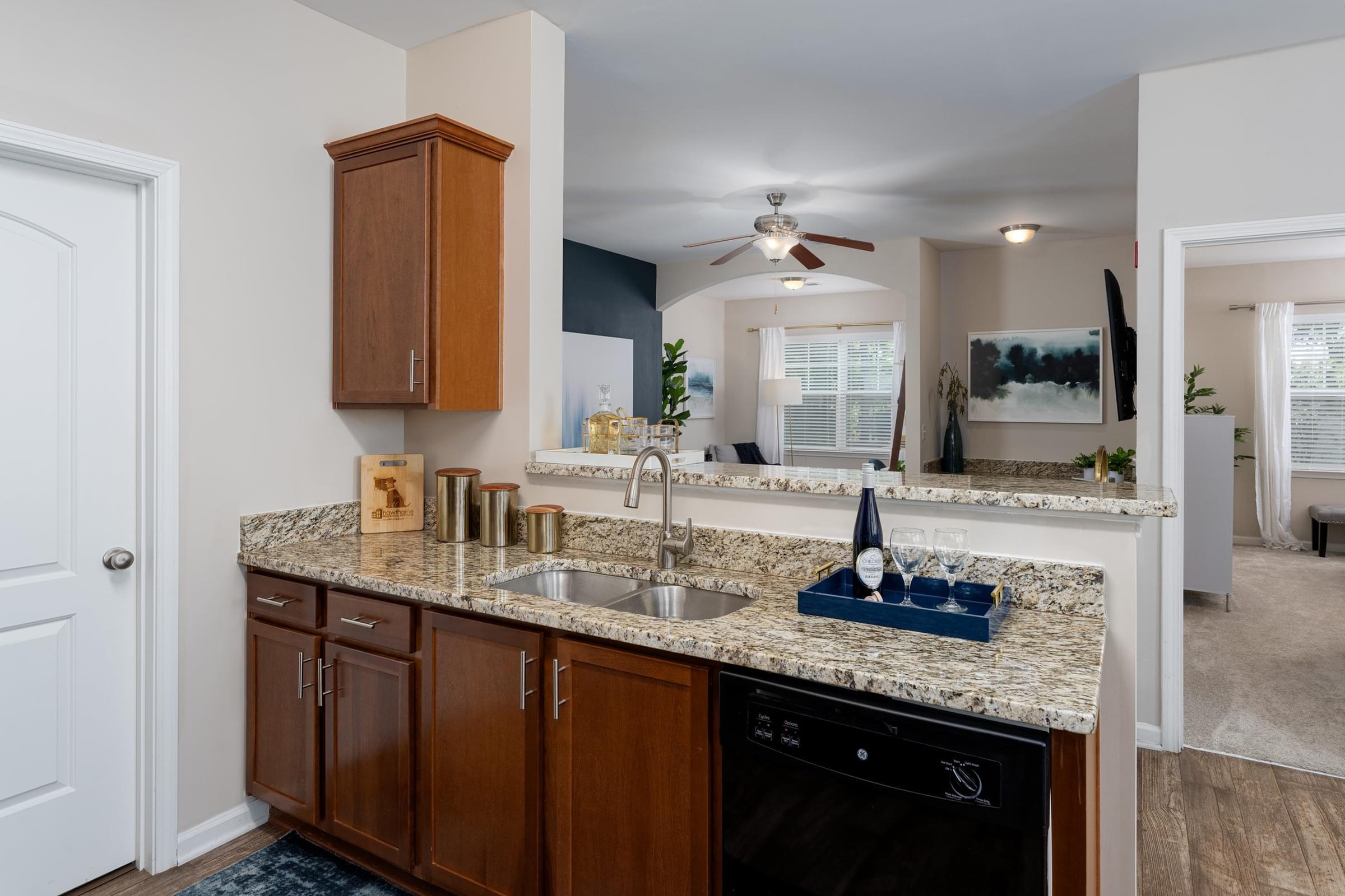 A kitchen with a black dishwasher and brown cabinets.