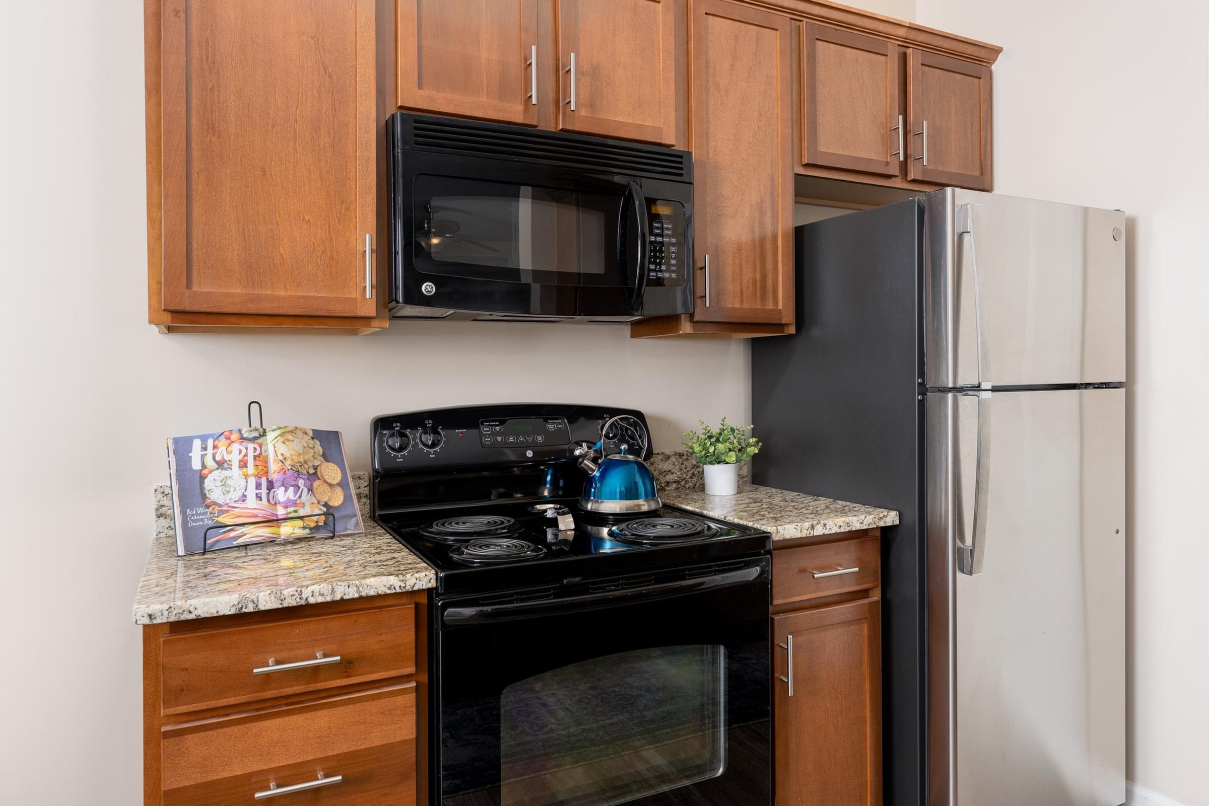 A black microwave oven is mounted above a black stove in a kitchen.