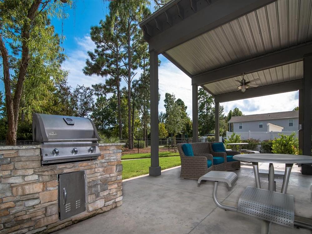 a covered patio with a grill and a table and chairs