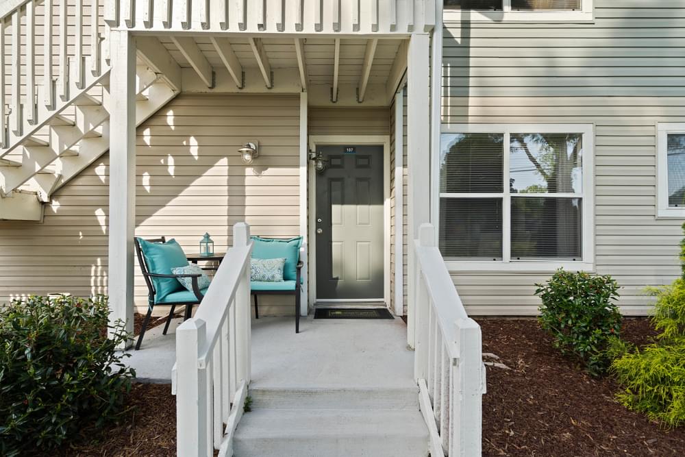 the front porch of a home with a porch swing and a white door