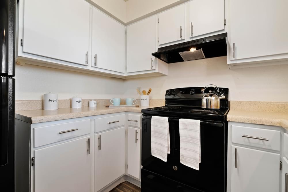 a kitchen with white cabinets and black appliances and a stove