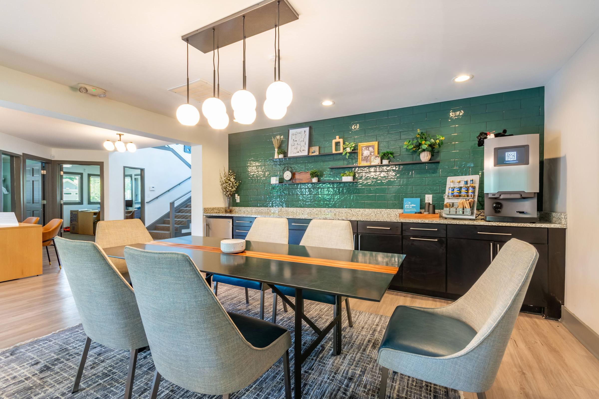 A modern clubhouse kitchen with a dining table and chairs at Hawthorne at Oak Ridge in Greensboro, NC.