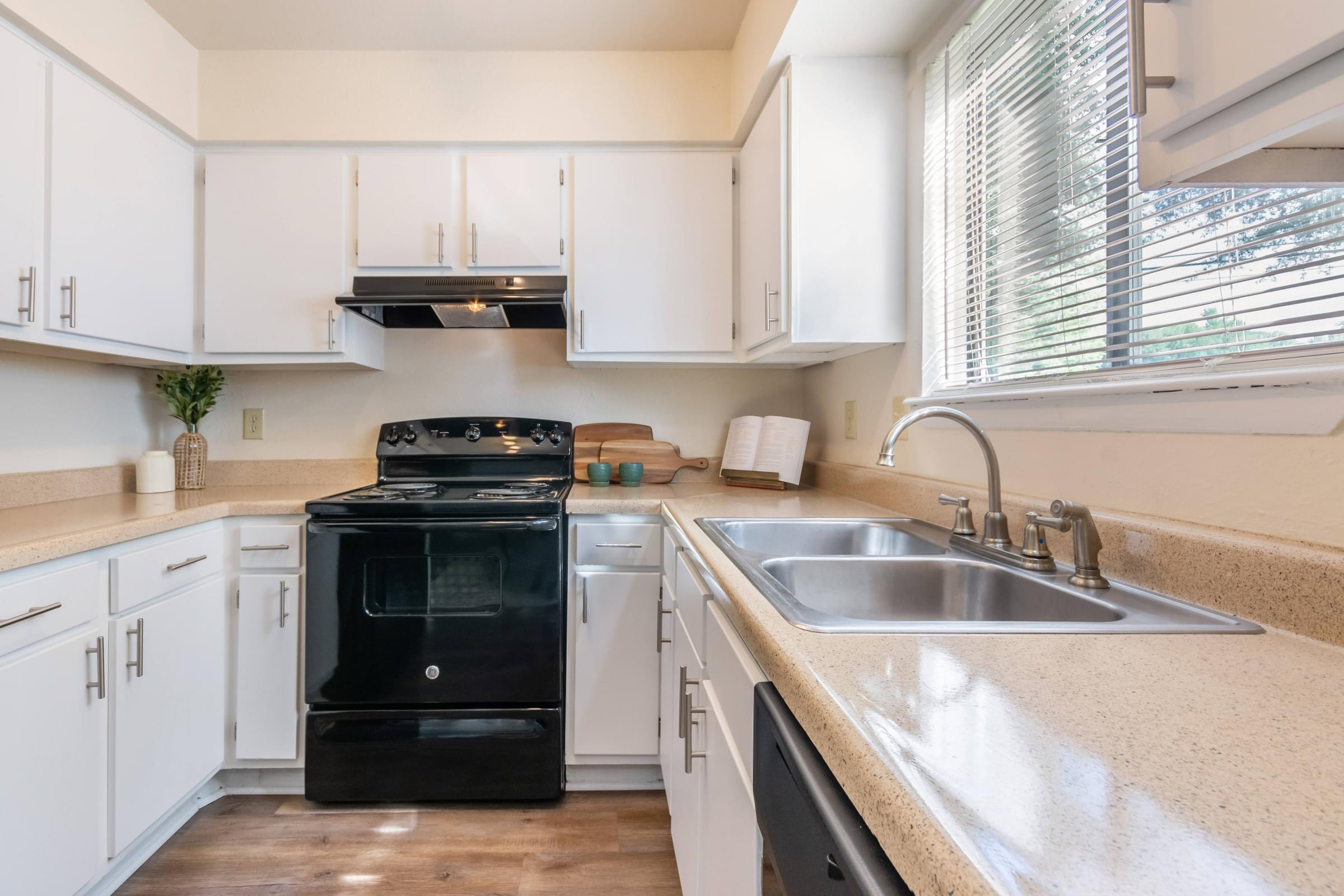 A black oven sits in a kitchen with white cabinets at Hawthorne at Oak Ridge in Greensboro, NC.