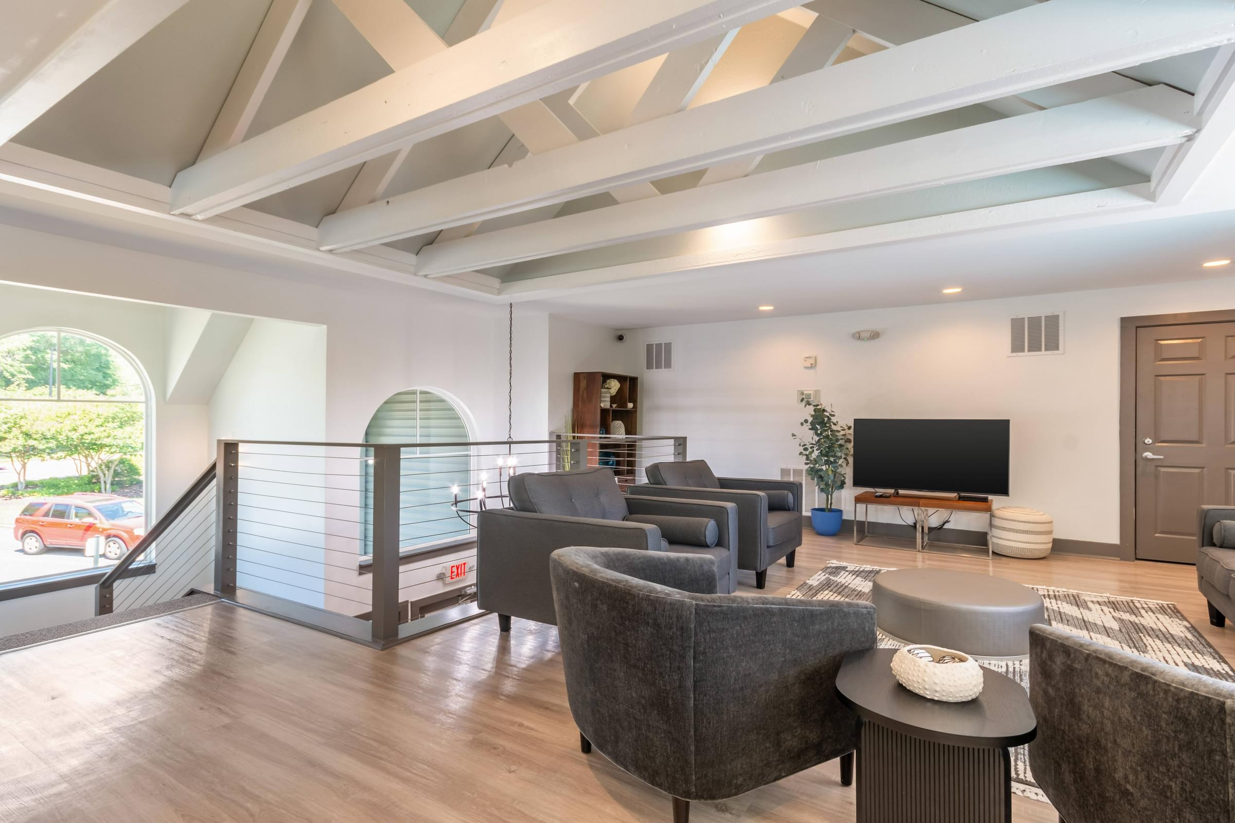 A seating area with a grey sofa and a television at Hawthorne at Oak Ridge in Greensboro, NC.