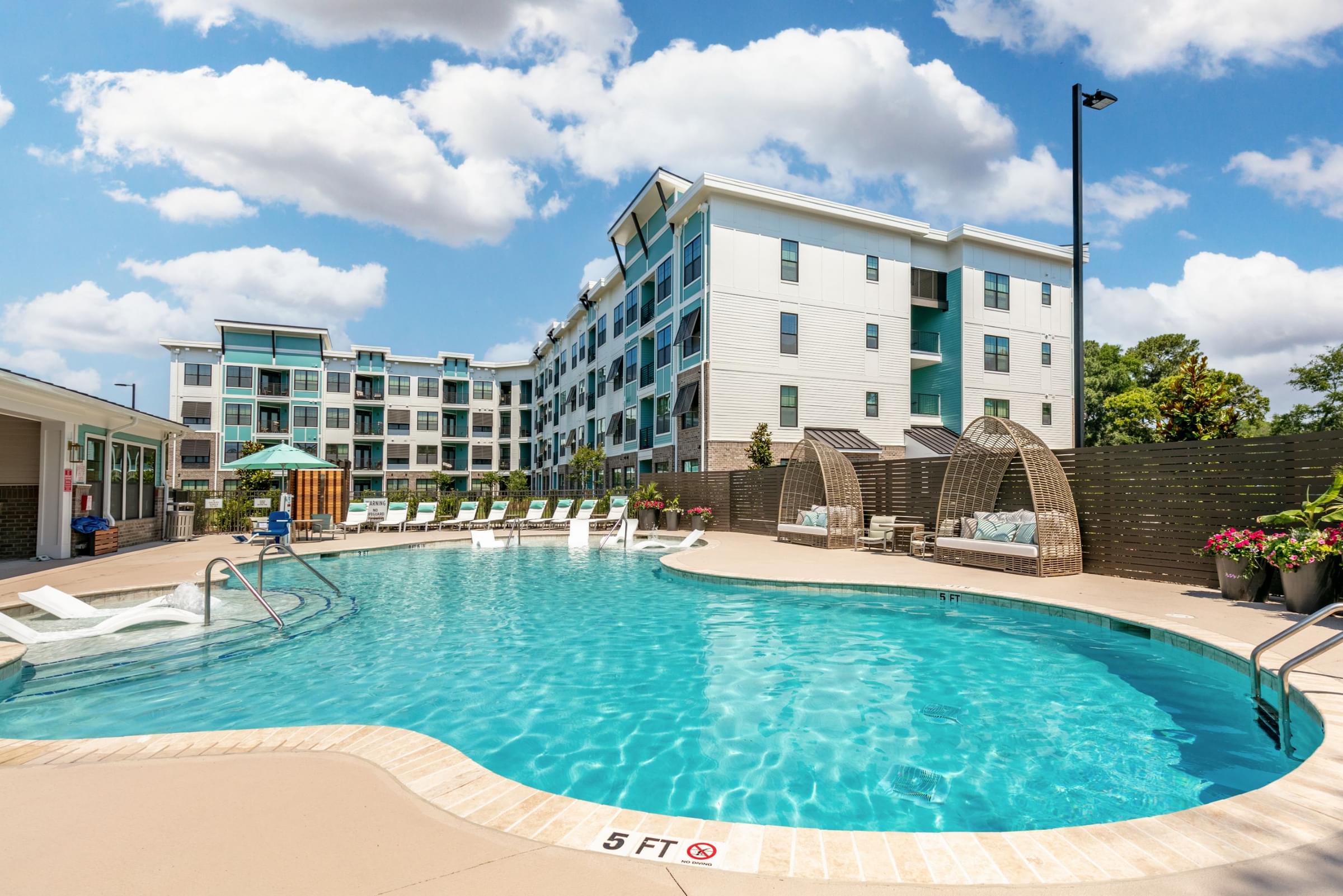 Resort Style Pool with Spacious Sundeck with Poolside Cabanas and Cushioned Lounge Furniture