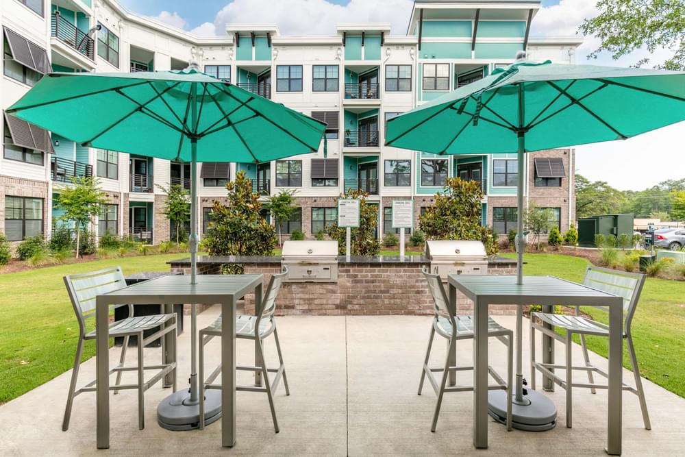 a patio with tables and umbrellas in front of an apartment building