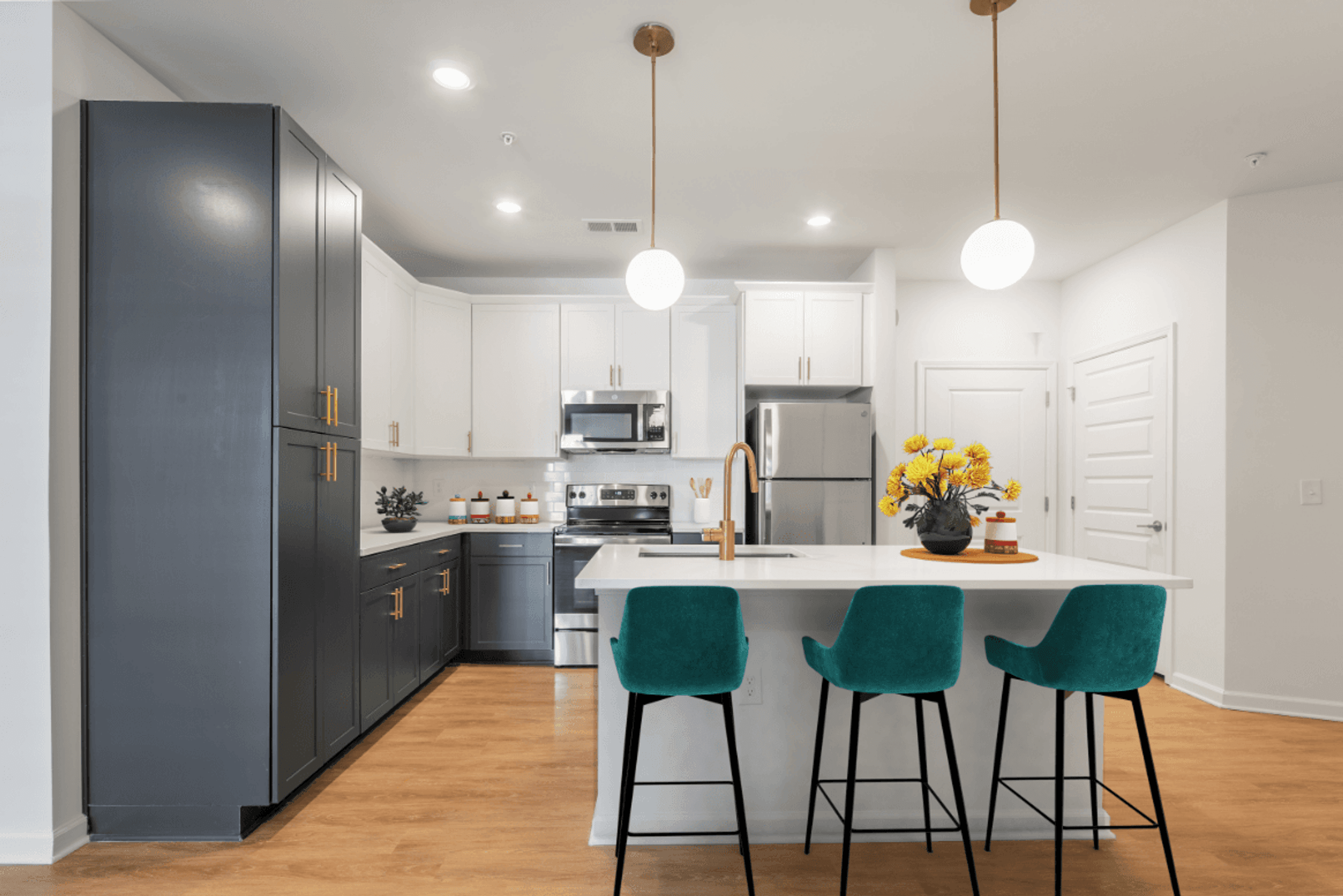 a kitchen with white cabinets and a white island with three green chairs