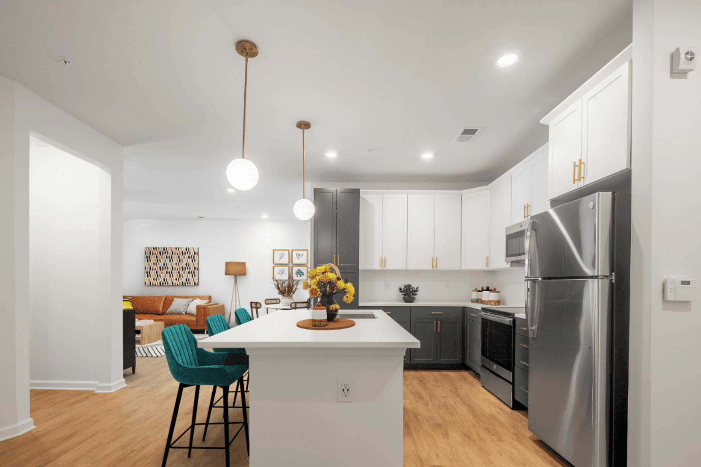 a kitchen and living room with a white counter top and stainless steel refrigerator