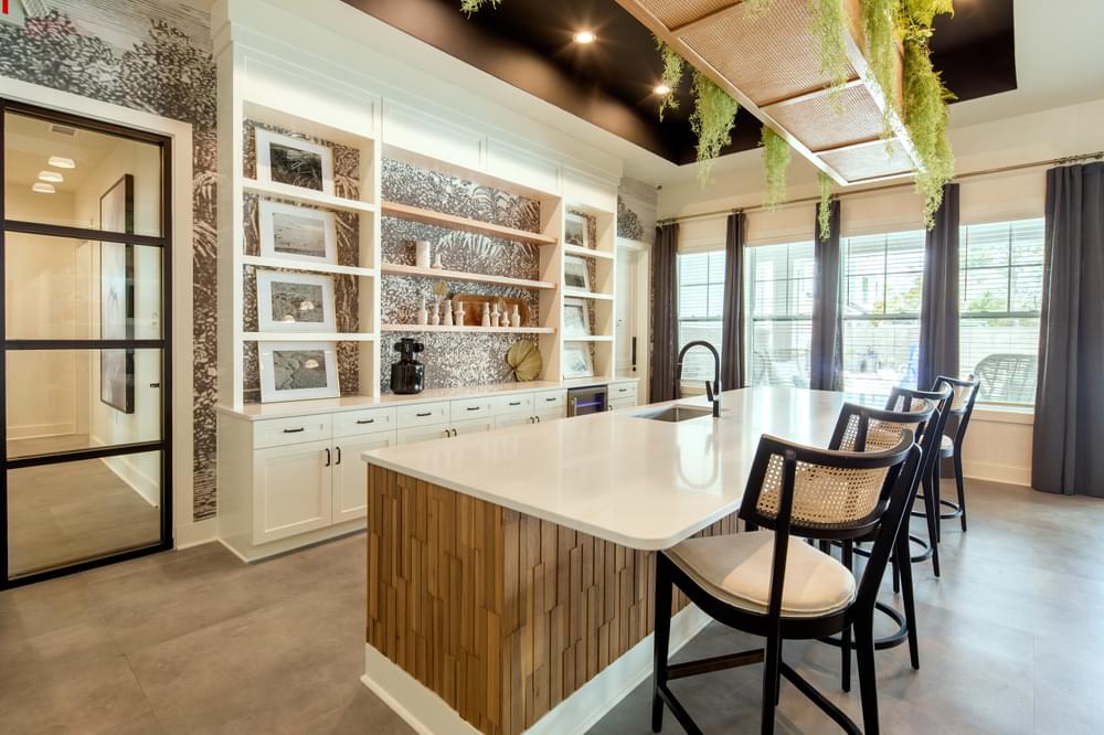 the kitchen has a large island with a marble countertop and a row of chairs