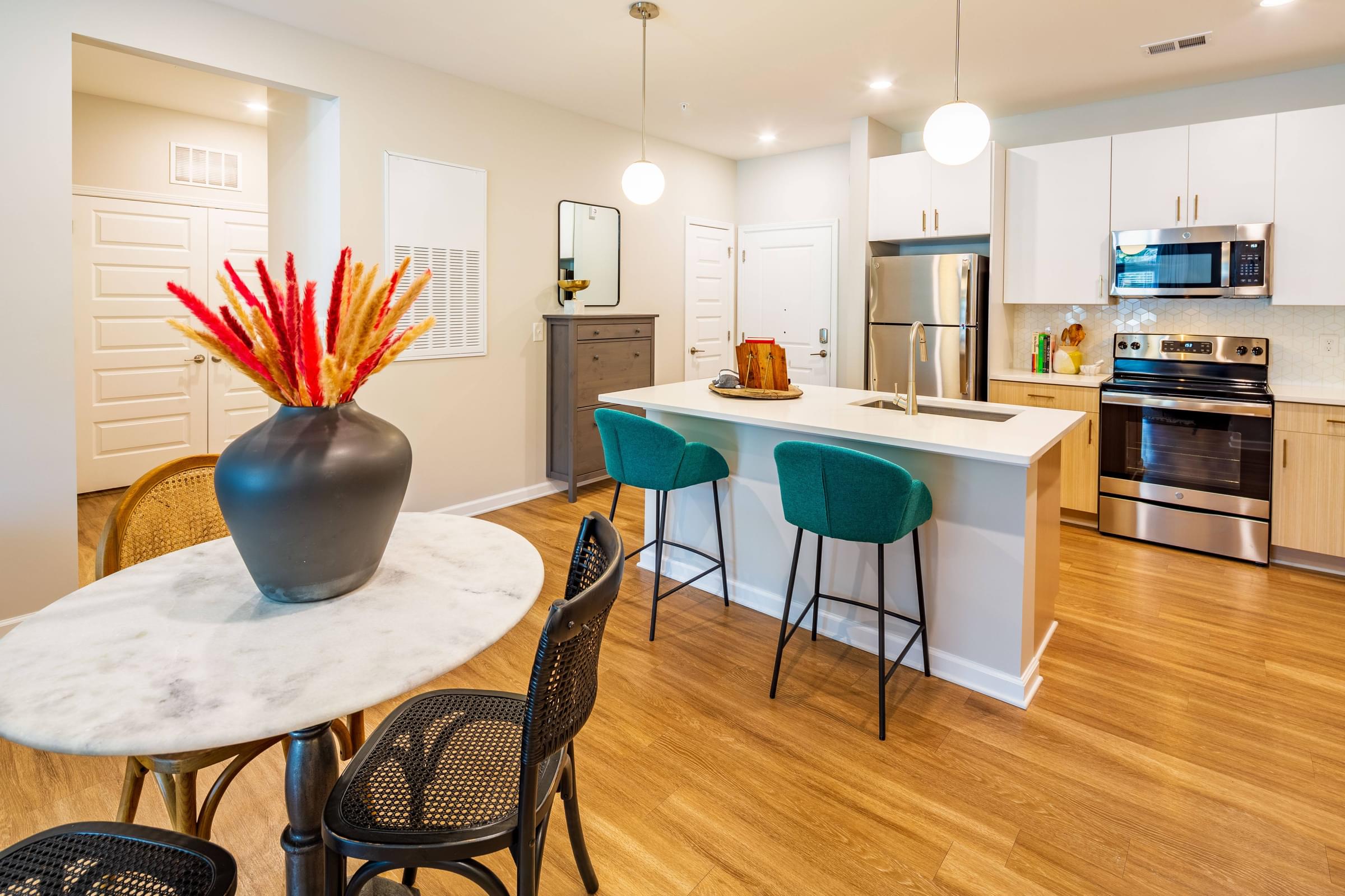 Spacious Dining Area that Peeks into the Open Kitchen with White Cabinets and Stainless Steel Appliances