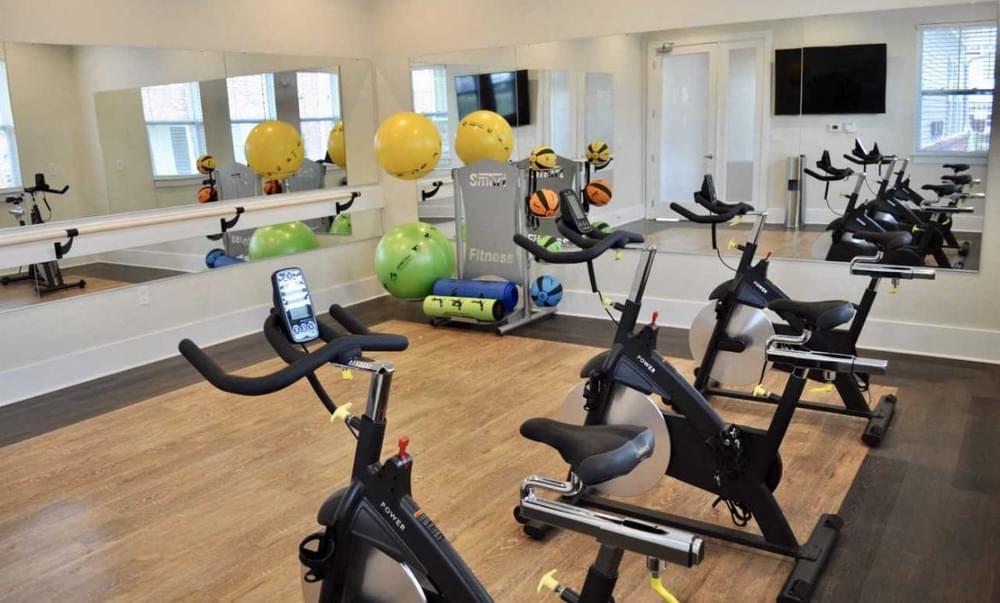 a gym with several exercise bikes and weights on a wooden floor