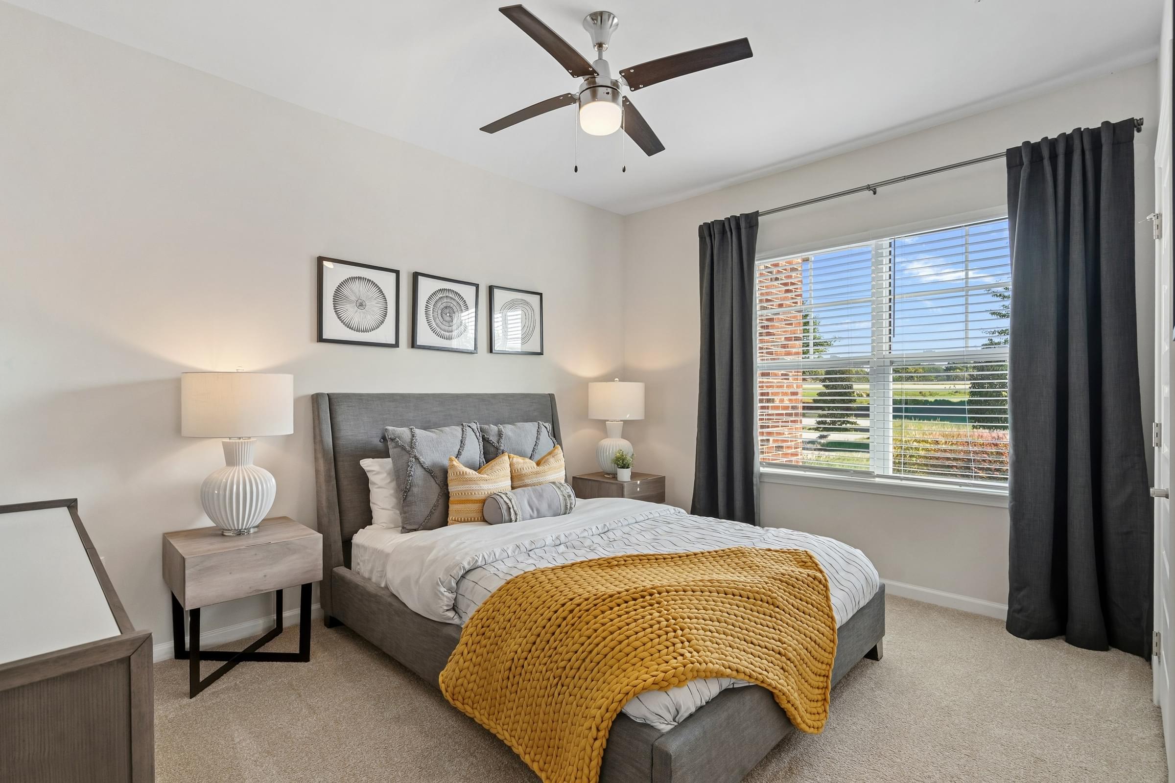 A bedroom with a bed, a ceiling fan, and a window with blinds.