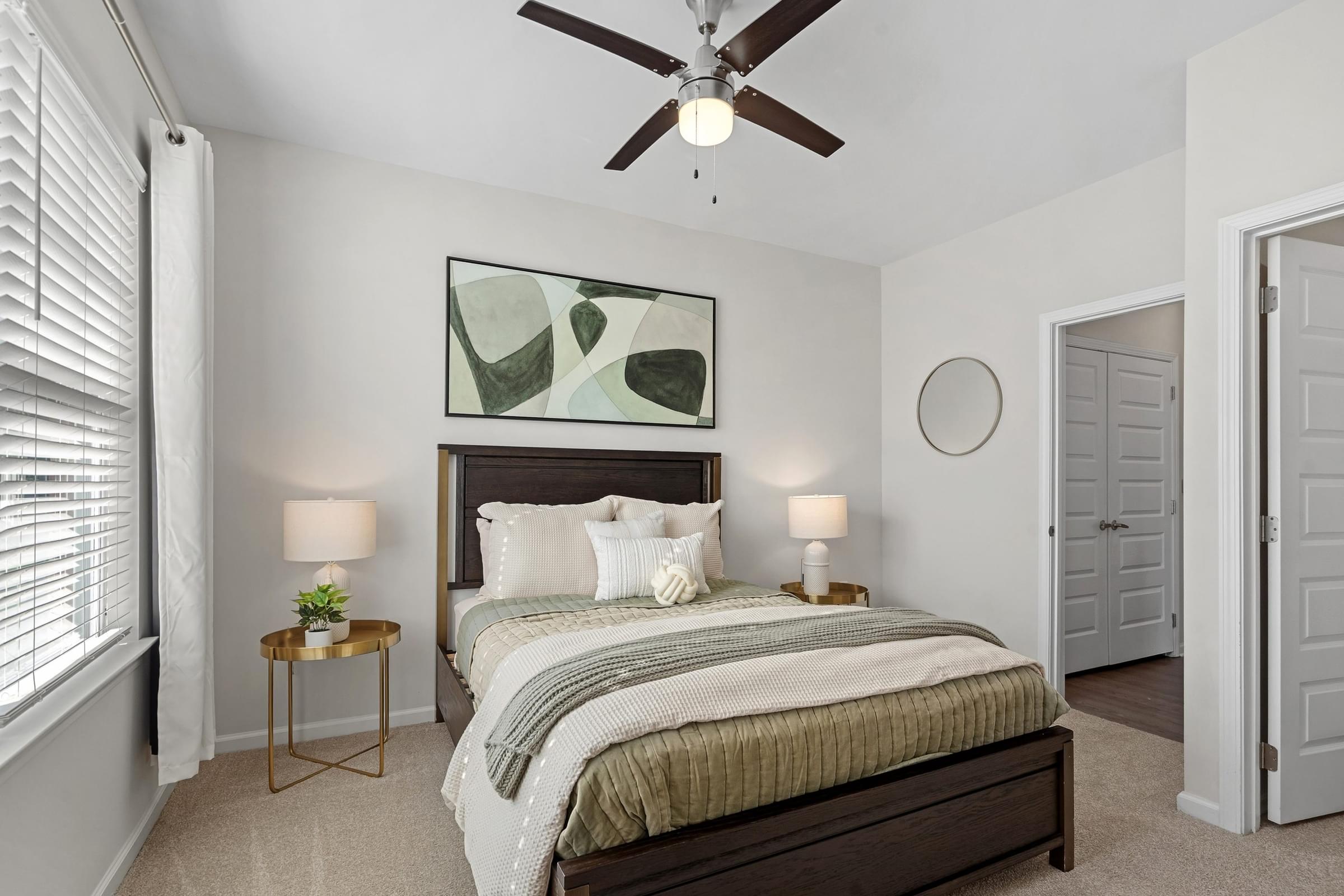 A bedroom with a bed, a ceiling fan, and a painting on the wall.