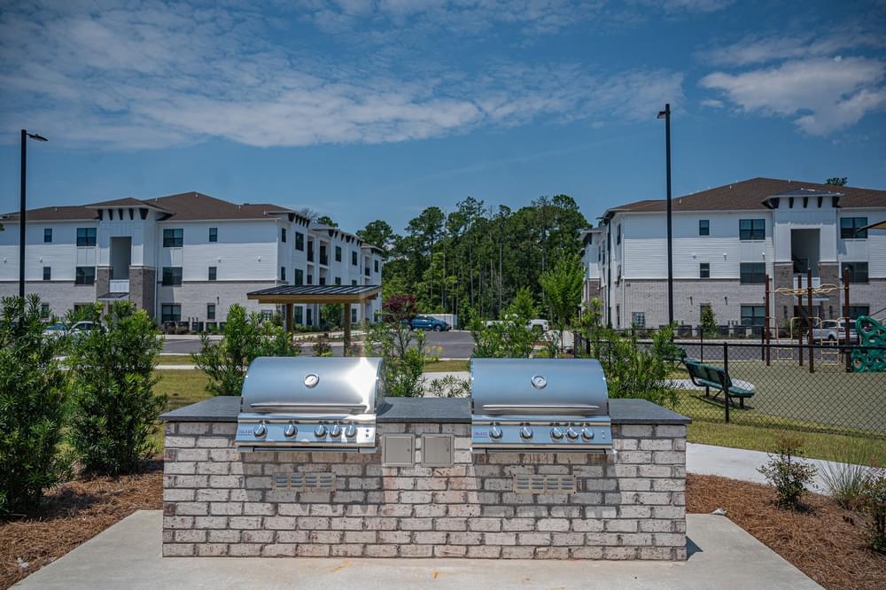 two bbq pits in front of apartments on a sunny day
