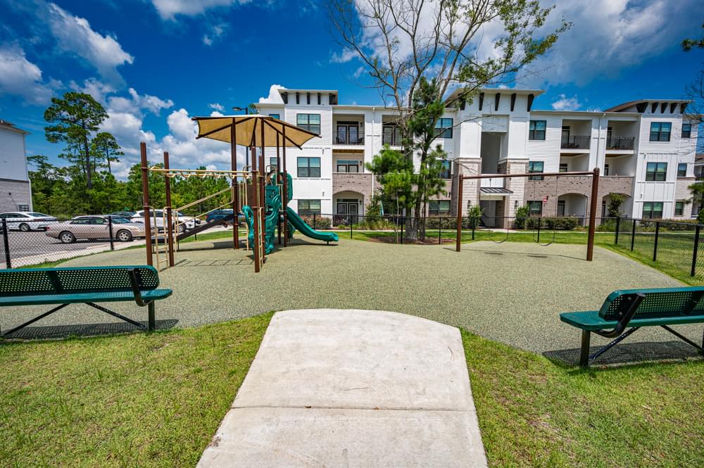 a playground with benches and a swing set in front of an apartment building
