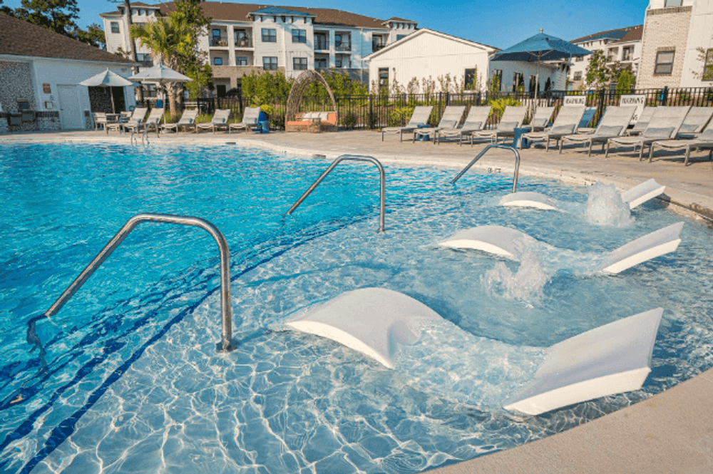 a swimming pool at a resort with chaise lounge chairs