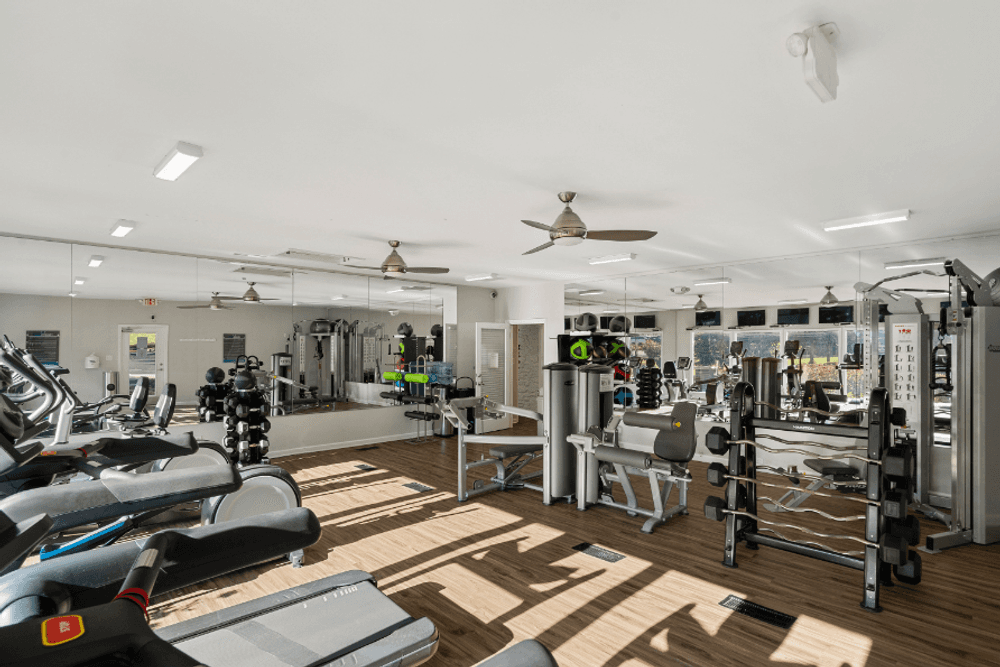 a gym with weights and cardio machines and a ceiling fan