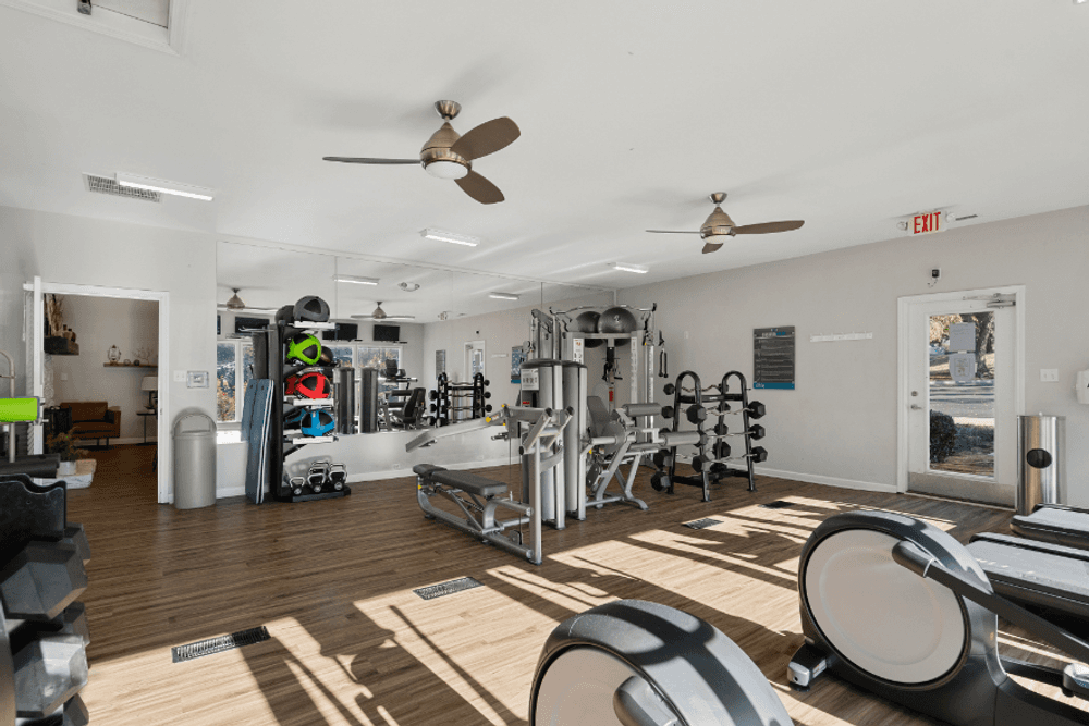 a gym with weights and cardio machines and ceiling fans