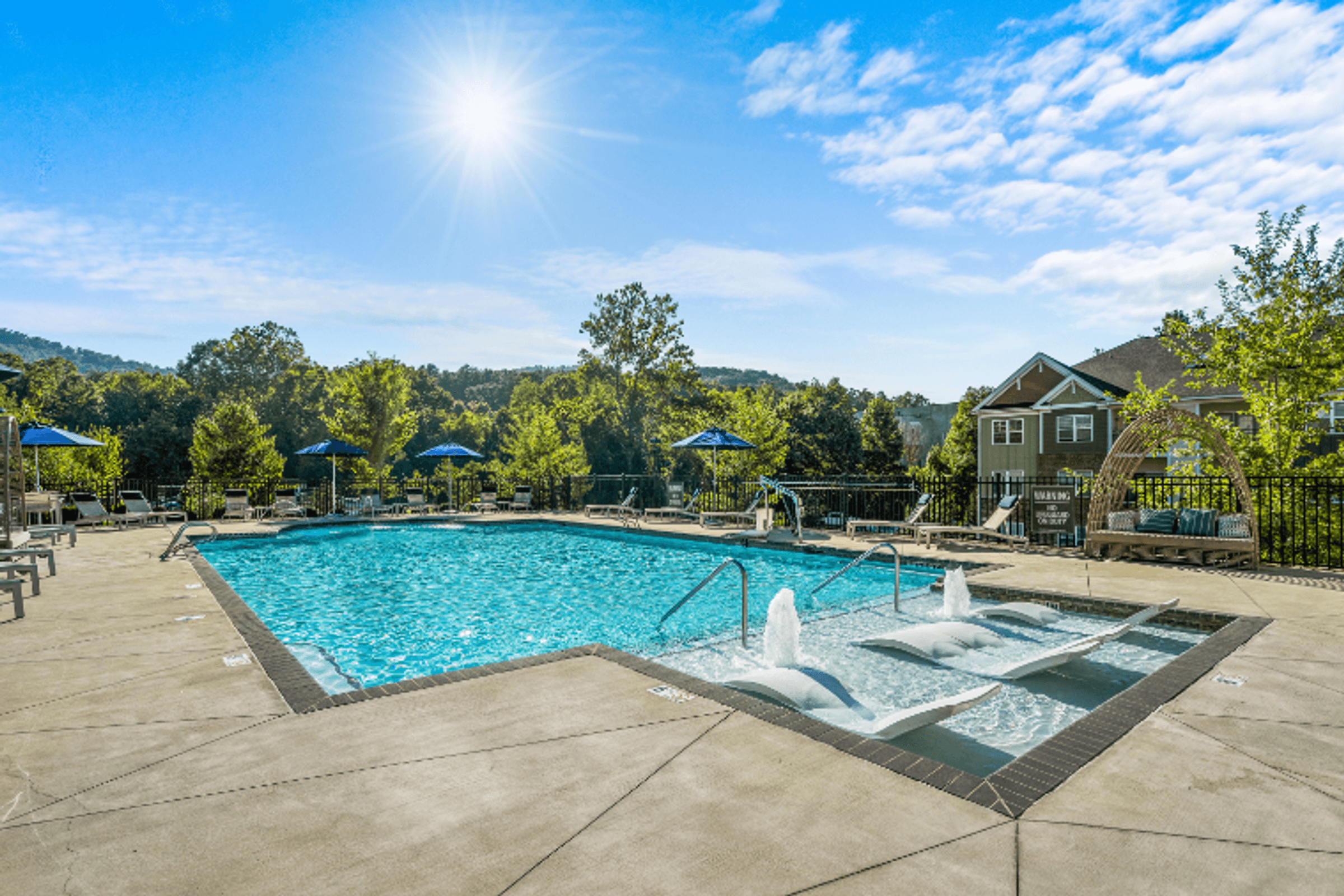 our resort style swimming pool is surrounded by seating areas and umbrellas