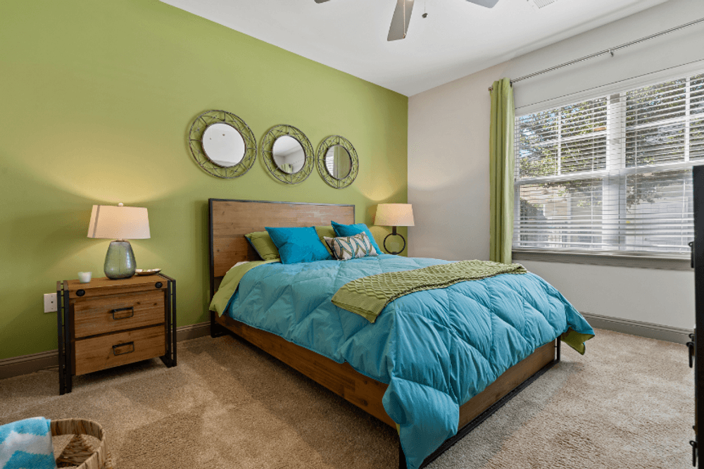 a bedroom with green walls and a bed with a blue comforter