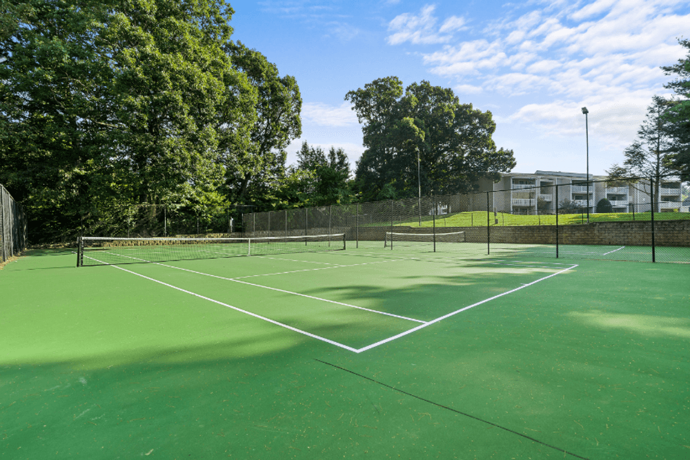 a tennis court on a sunny day with trees