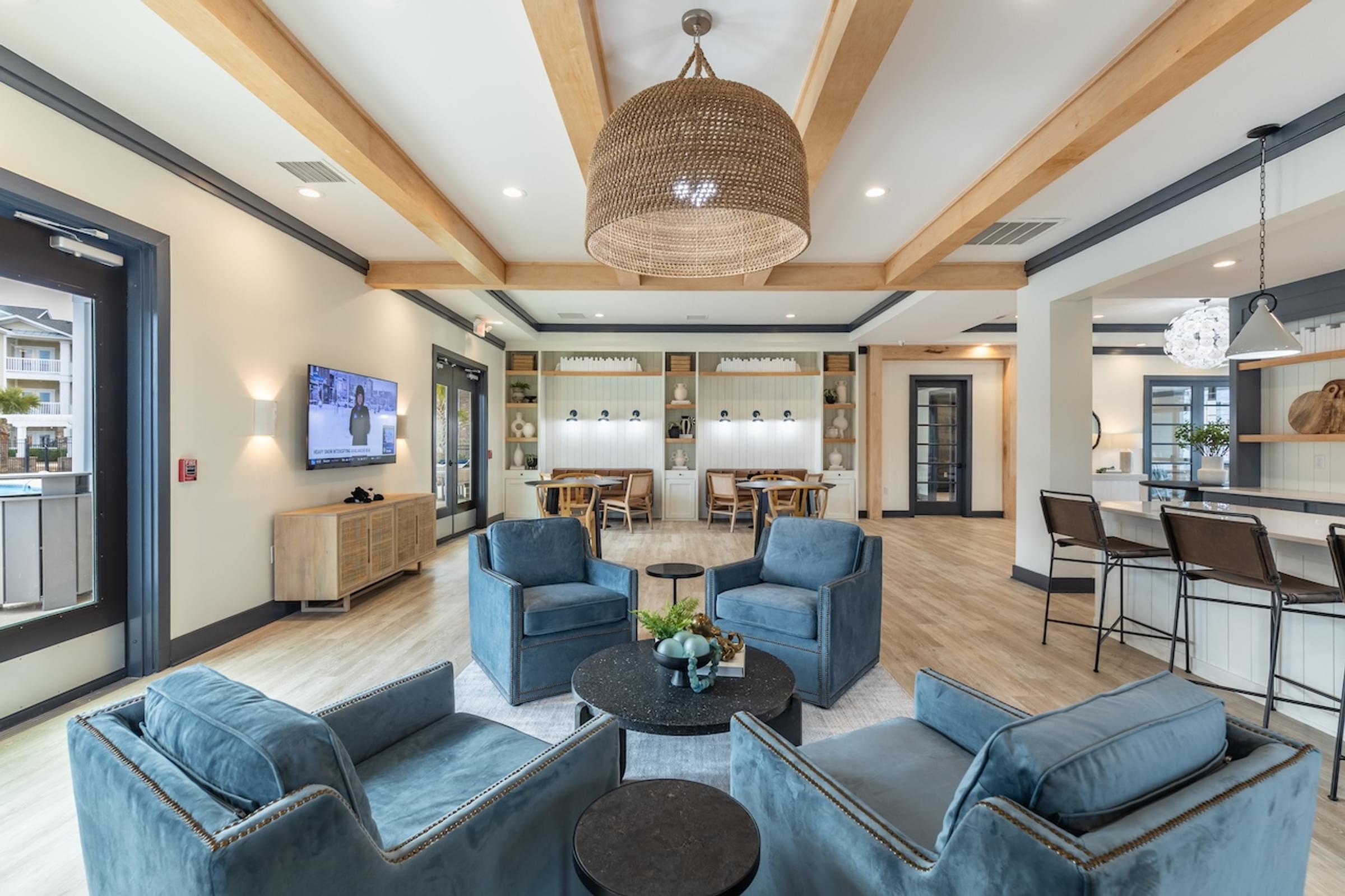 a living room with blue couches and chairs and a dining room with a table