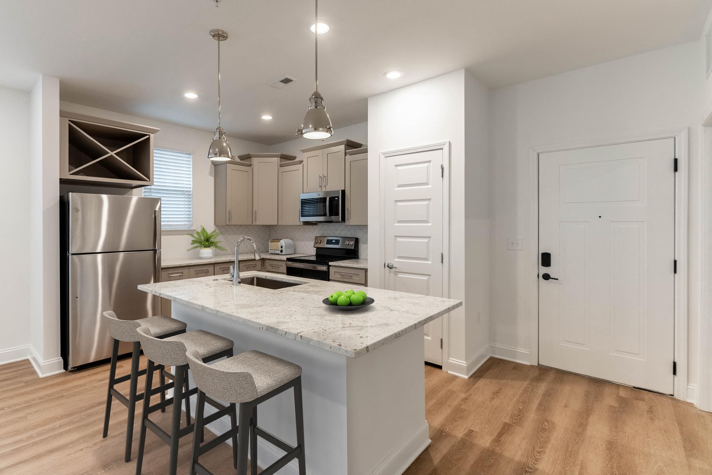 A kitchen with a white countertop and bar stools.