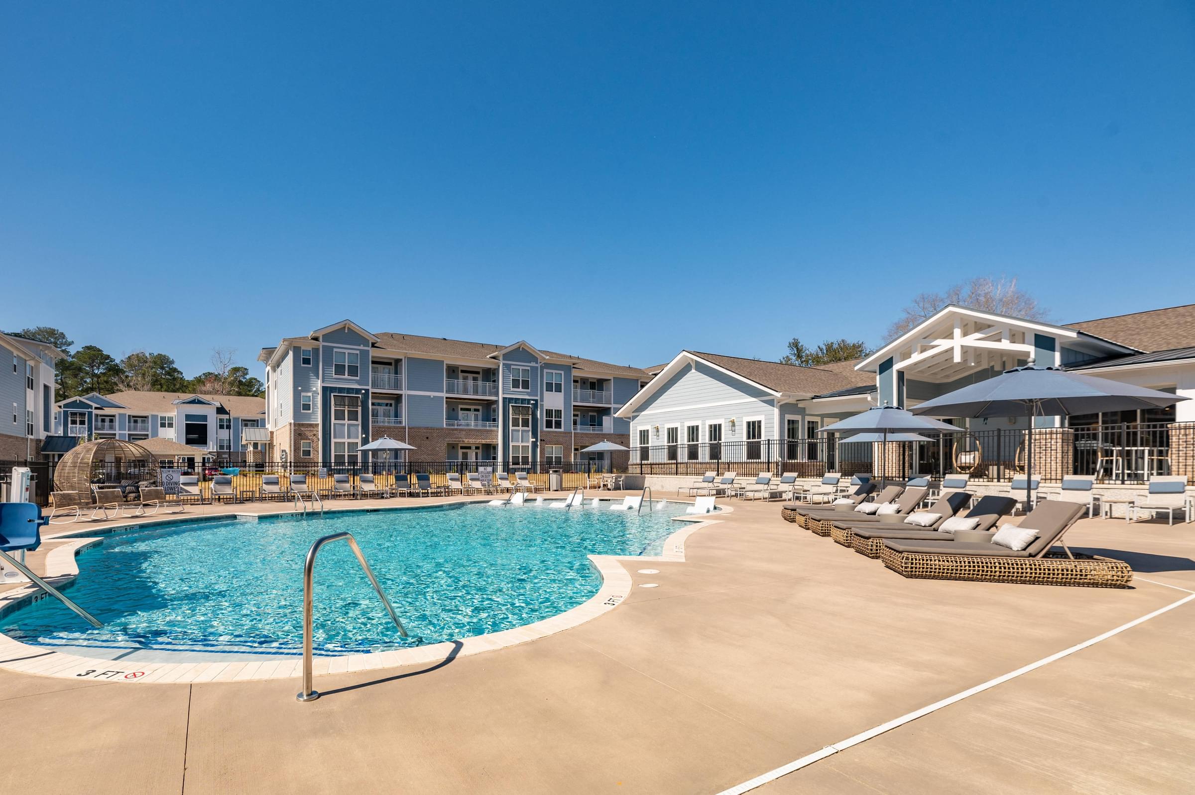 a swimming pool with lounge chairs in front of a building