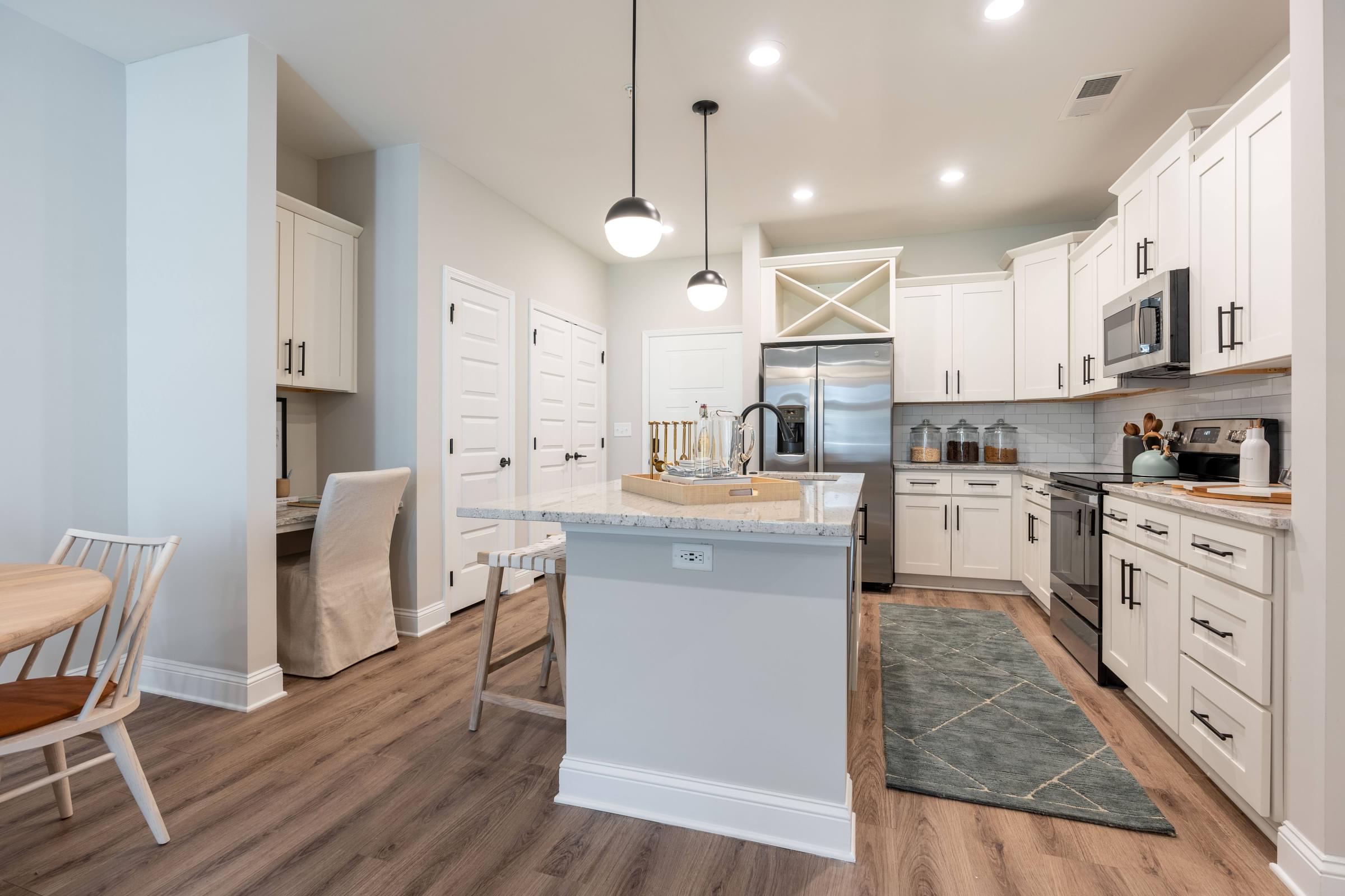 A kitchen with a white fridge, wooden floors, and white cabinets.