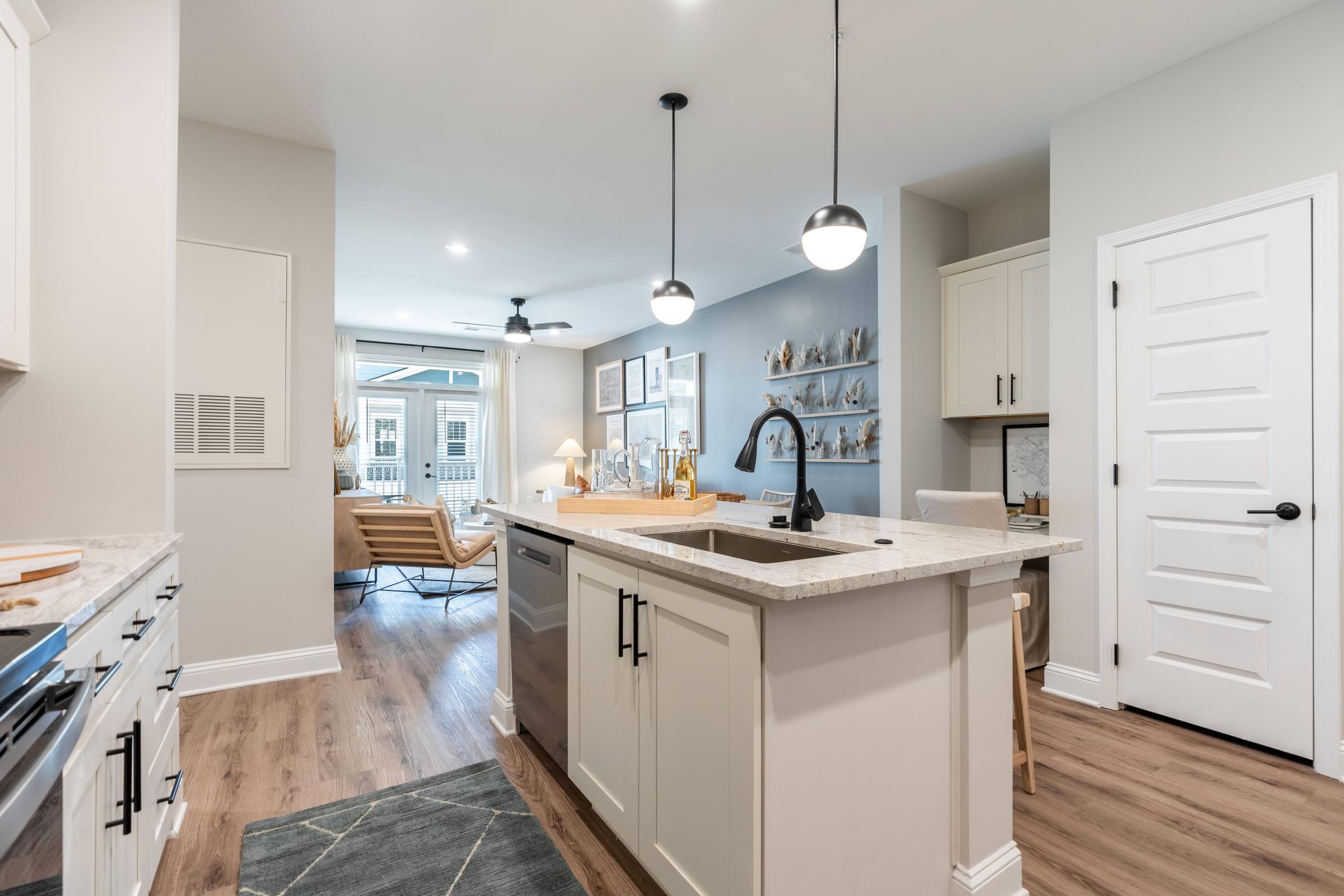 an open kitchen and living room with white cabinets and a sink