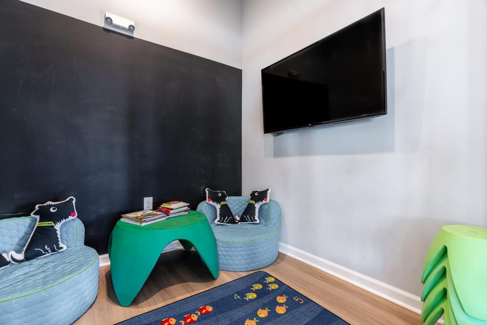 a living room with a black chalkboard wall and a green table