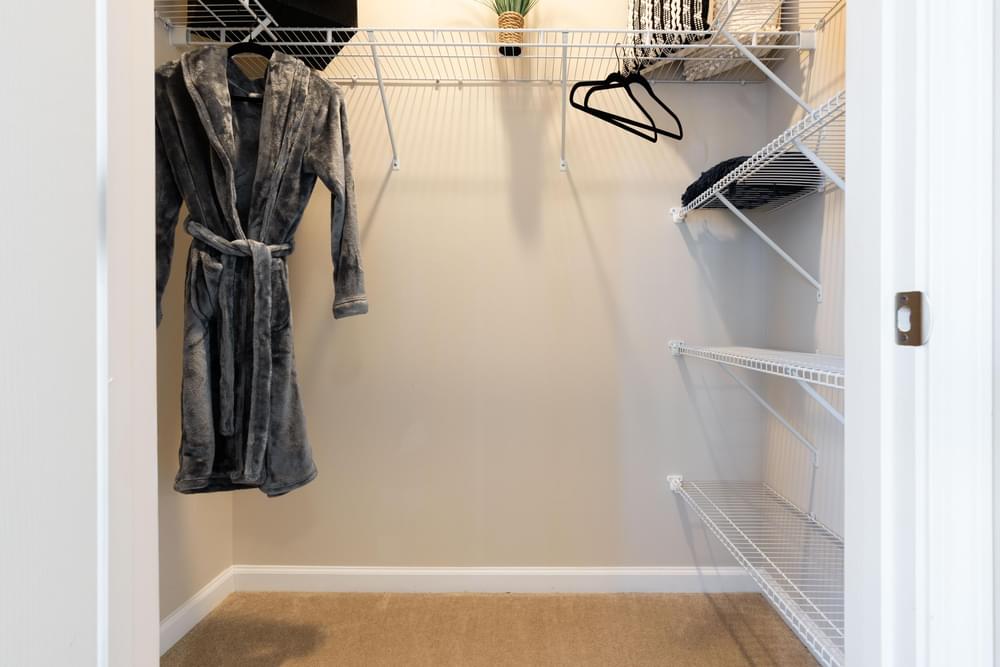 a walk in closet with a coat hanging on the wall