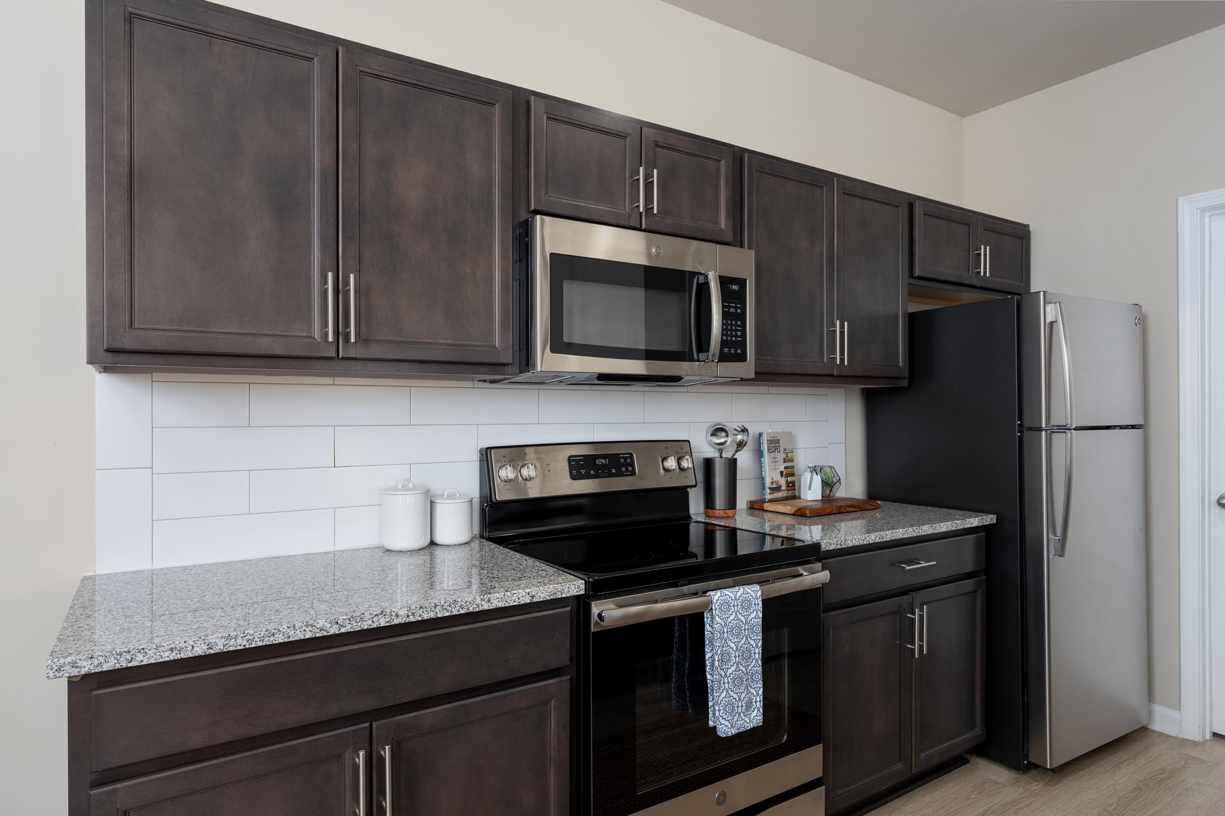 A kitchen with dark brown cabinets and black appliances.
