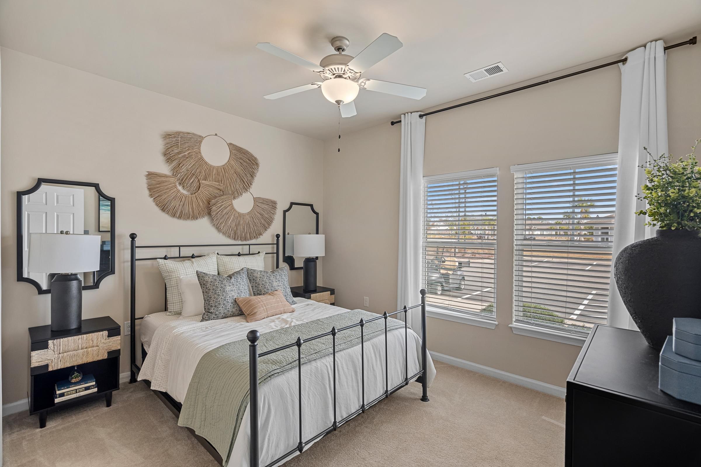 A bedroom with a bed, a fan, and a window with blinds.