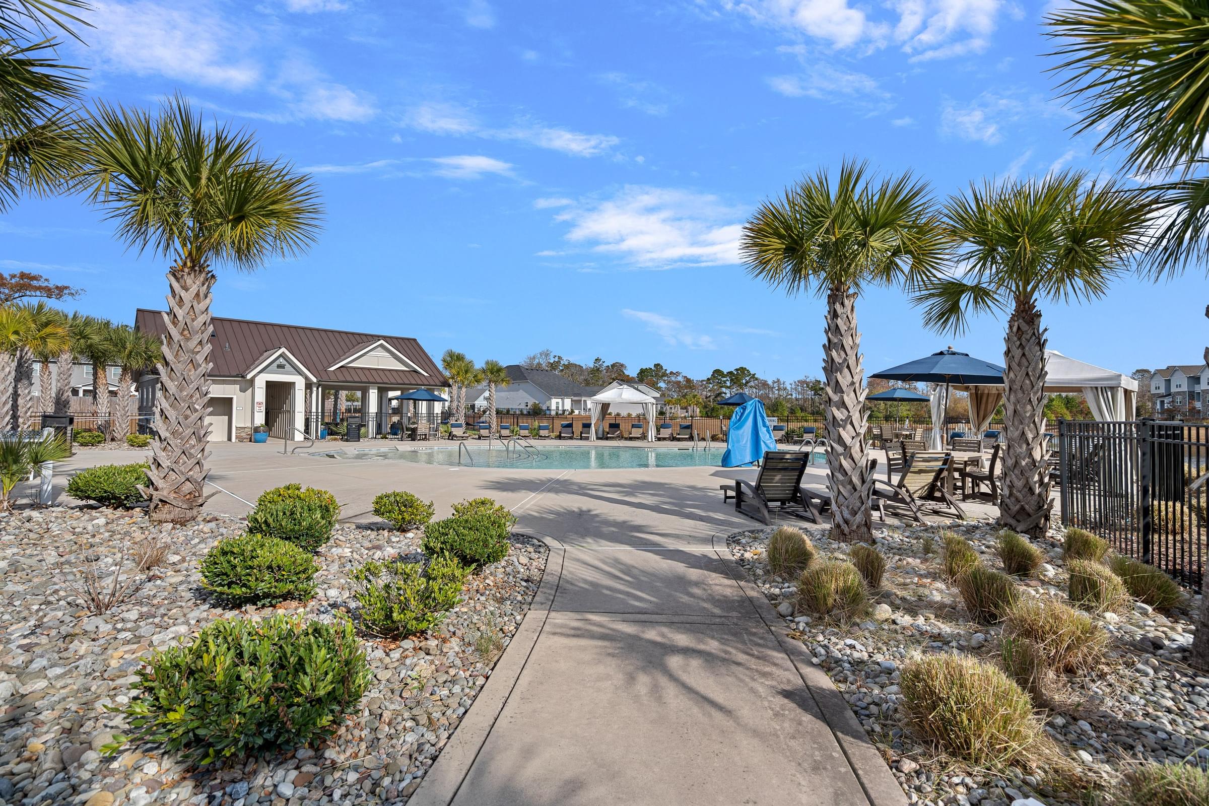 A sunny day at the community pool surrounded by palm trees and a building in the background.