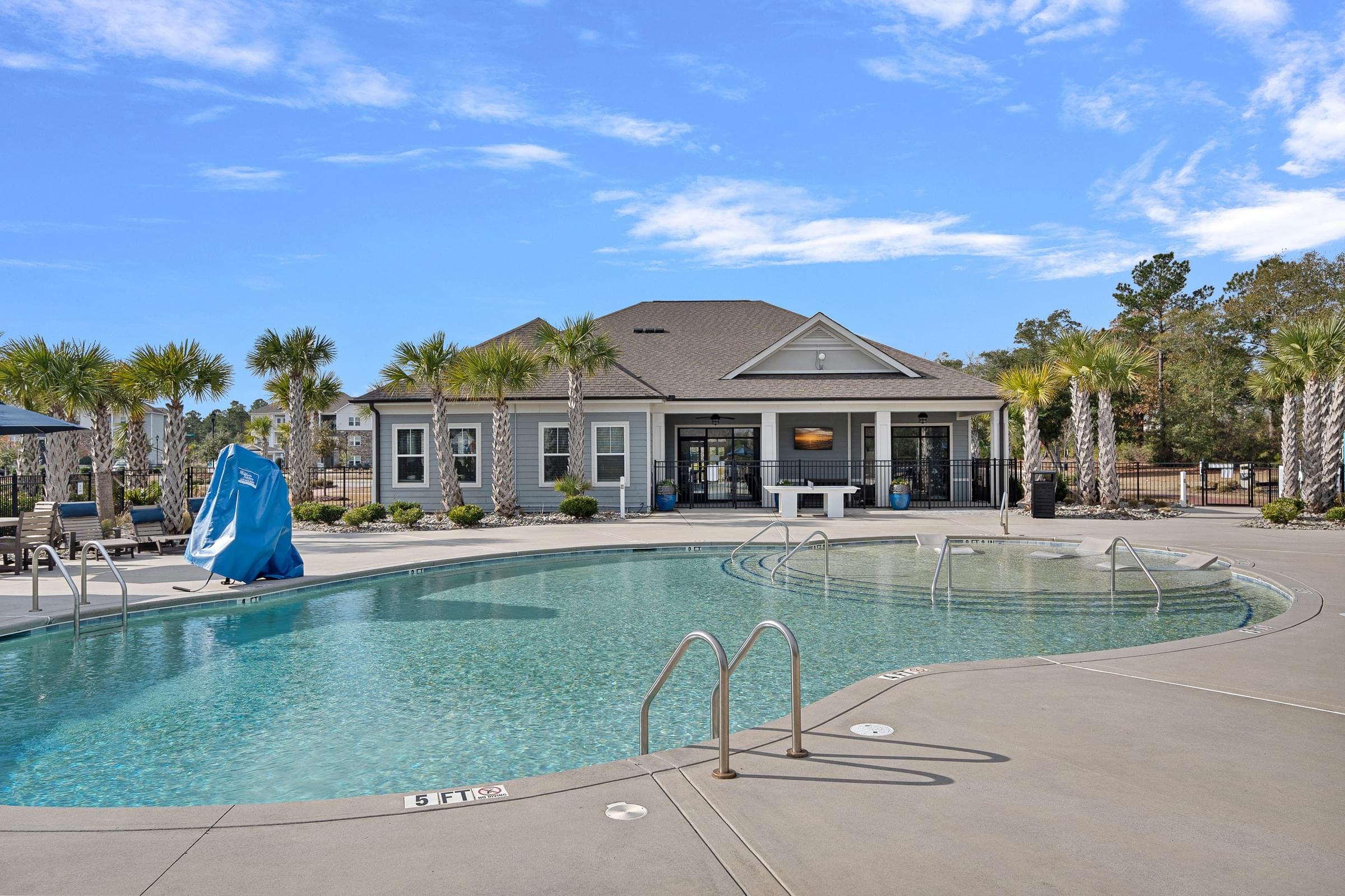 A swimming pool with a blue umbrella and a building in the background.