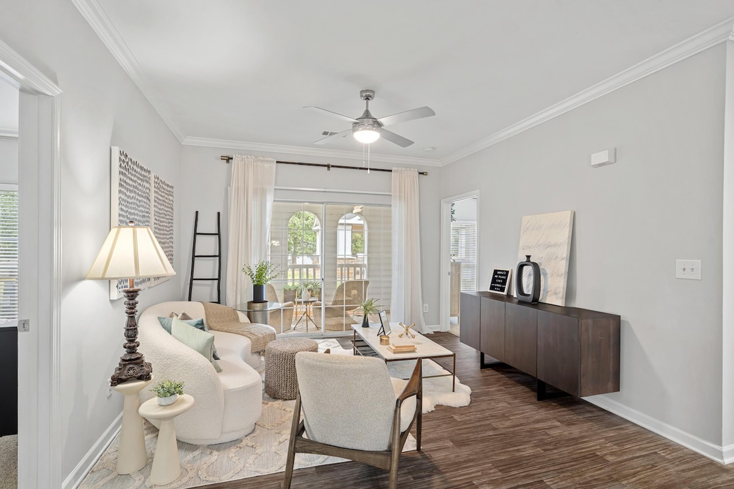 a living room with white walls and a ceiling fan