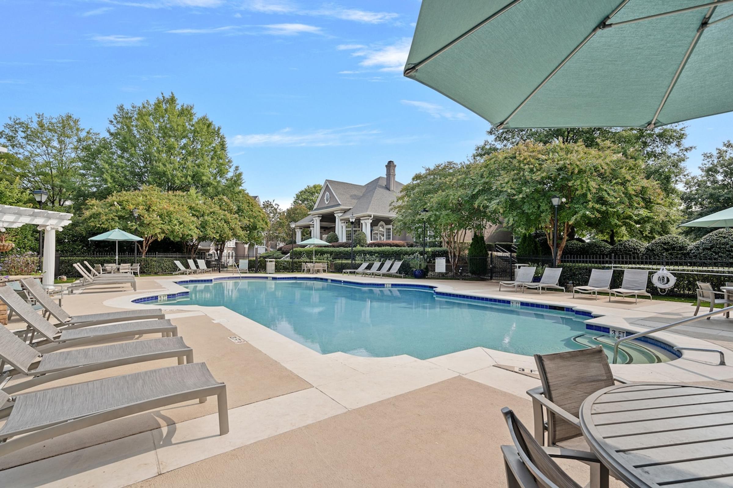 a swimming pool with chairs and a house in the background