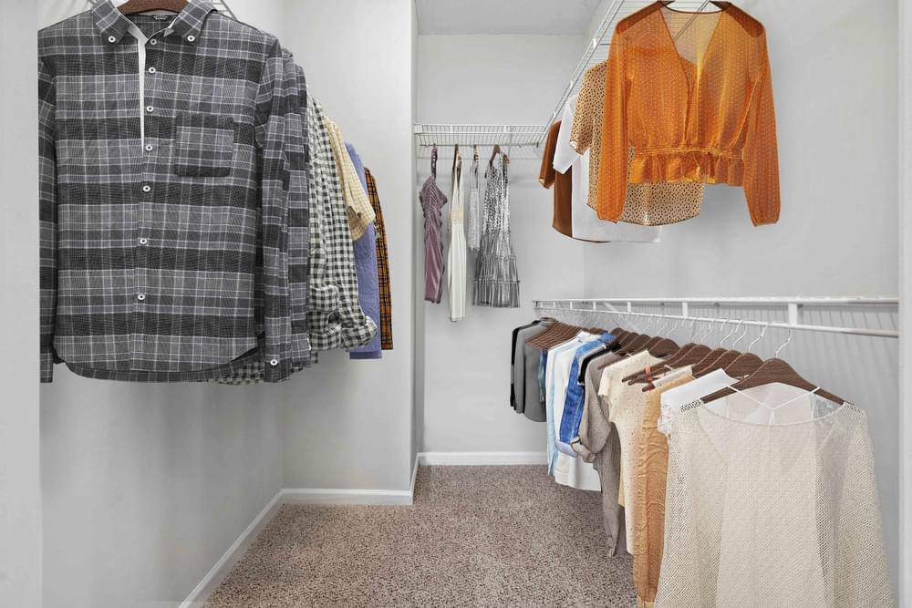 a walk in closet with clothes hanging on a rack and a carpeted floor