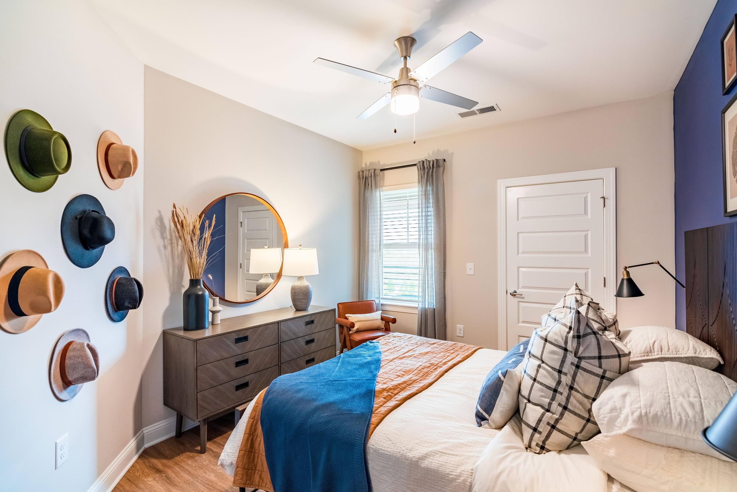 A bedroom with a bed, dresser, mirror, and wall decor